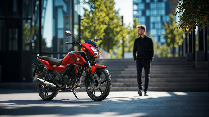 Honda CB125F w kolorze czerwonym na tle miejskiej zabudowy